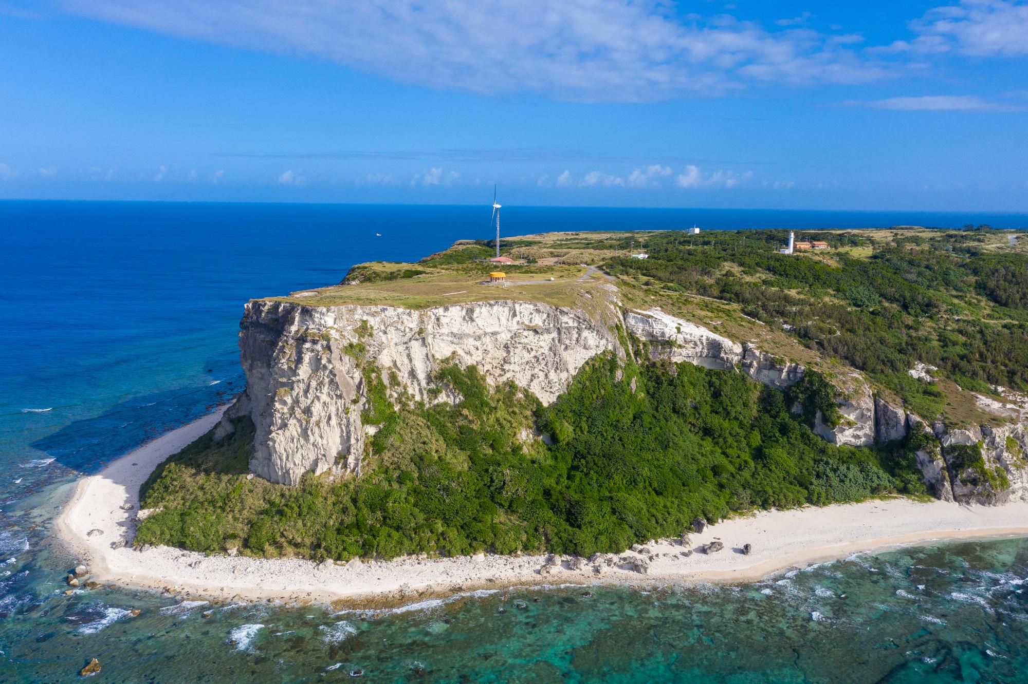 青空の下、白色凝灰岩をはらんだ断崖絶壁の筆ん崎を下から撮影した写真