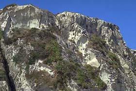 青空の下、白色凝灰岩をはらんだ断崖絶壁の筆ん崎を下から撮影した写真